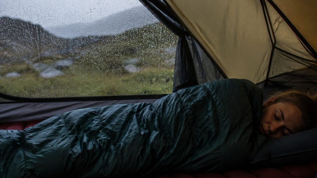 kvinde som sover i en sovepose i et telt